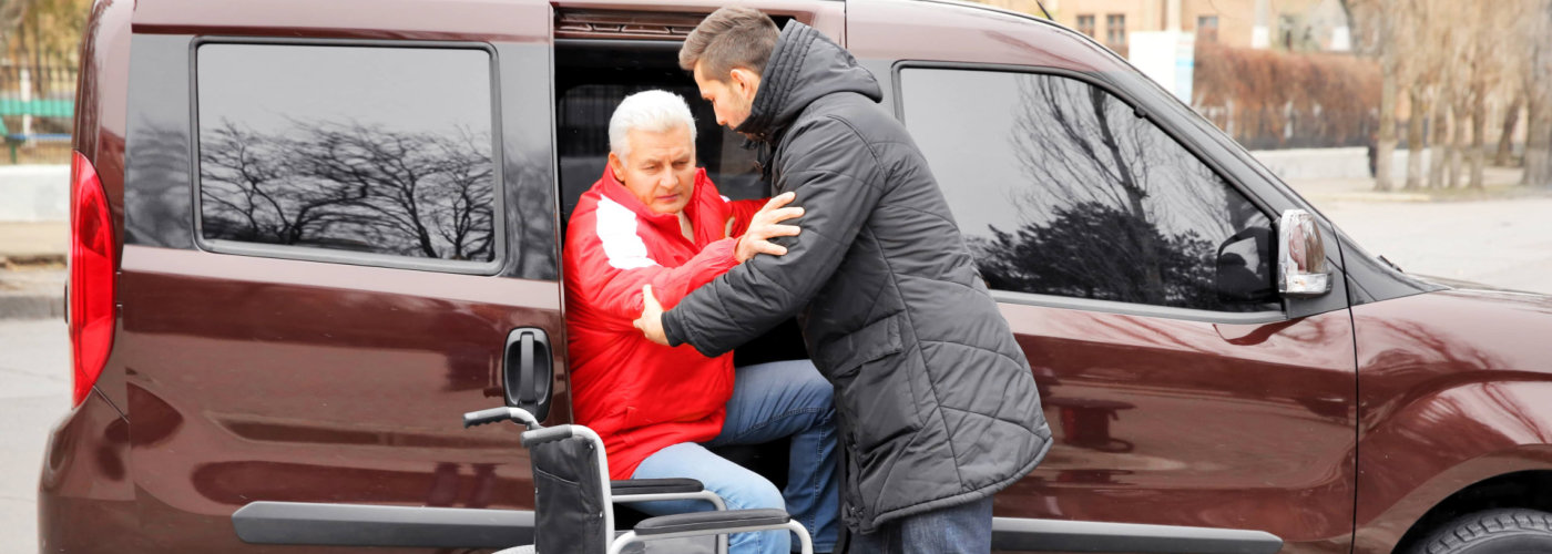 adult man assisting senior man in transportation