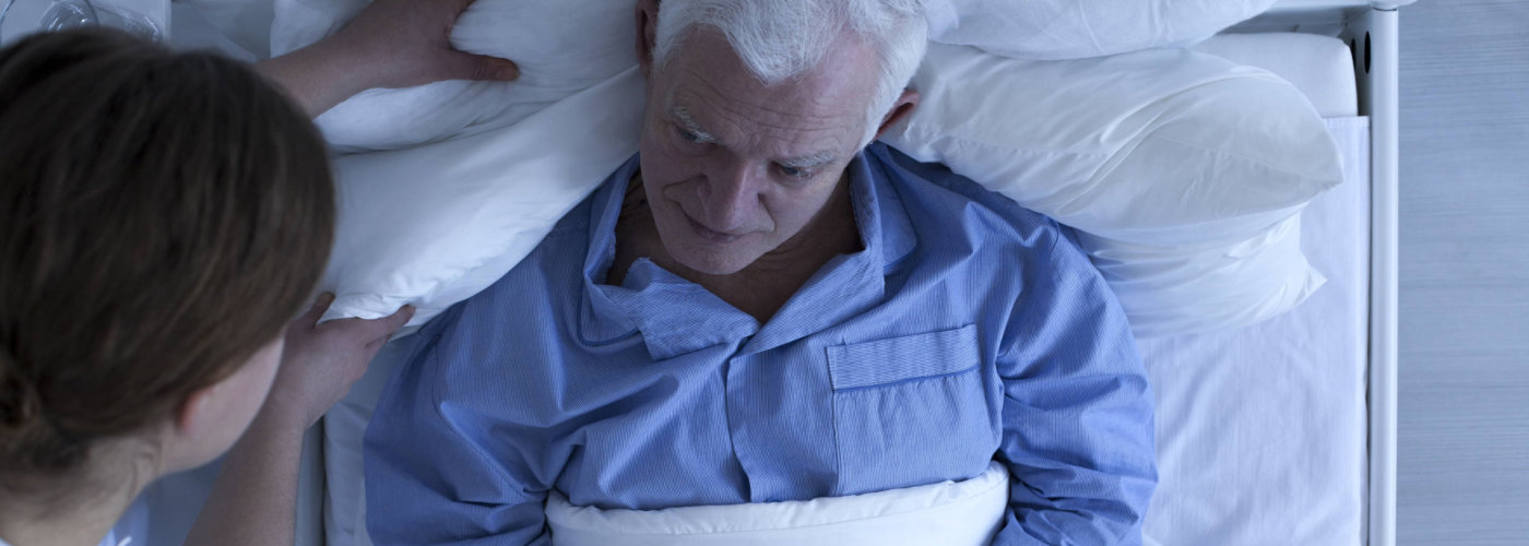 caregiver assisting senior man in sleeping
