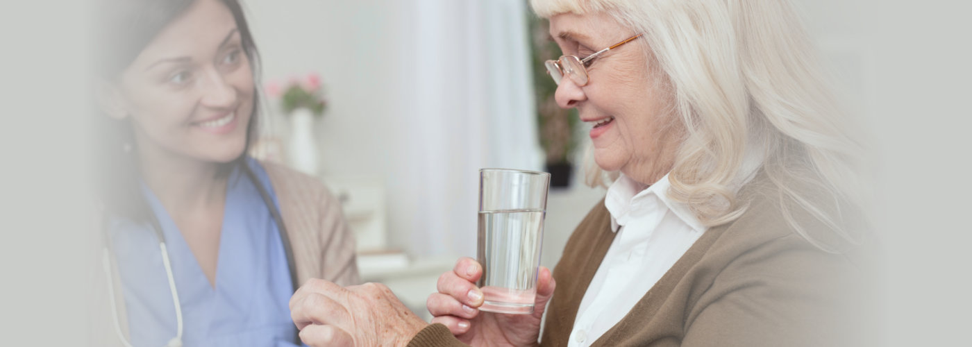 Positive mature woman taking pills from nurse while looking down